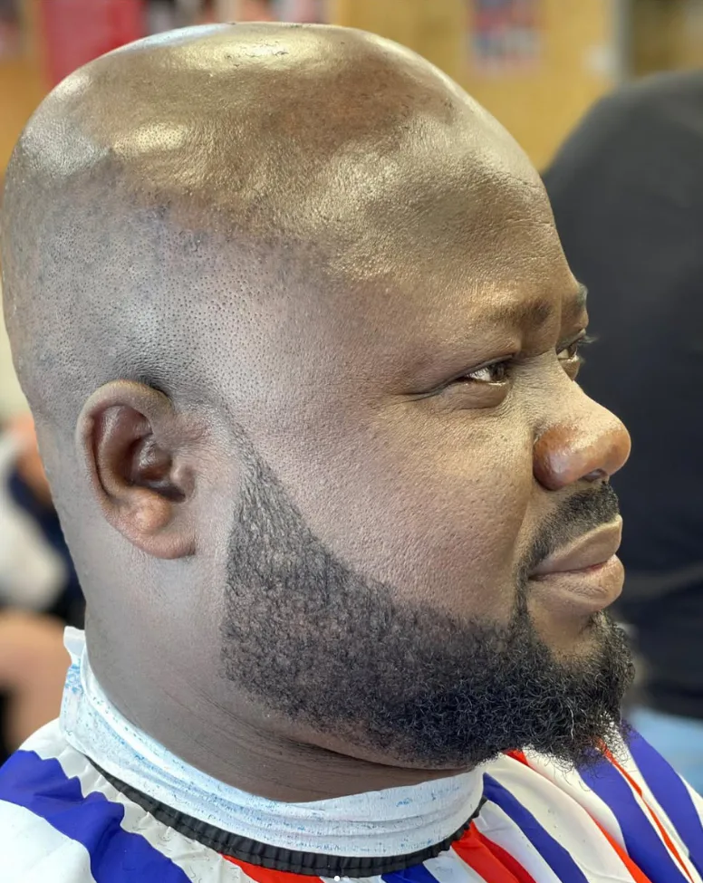 Close-up of a smooth head shave with a cleanly shaped full beard
