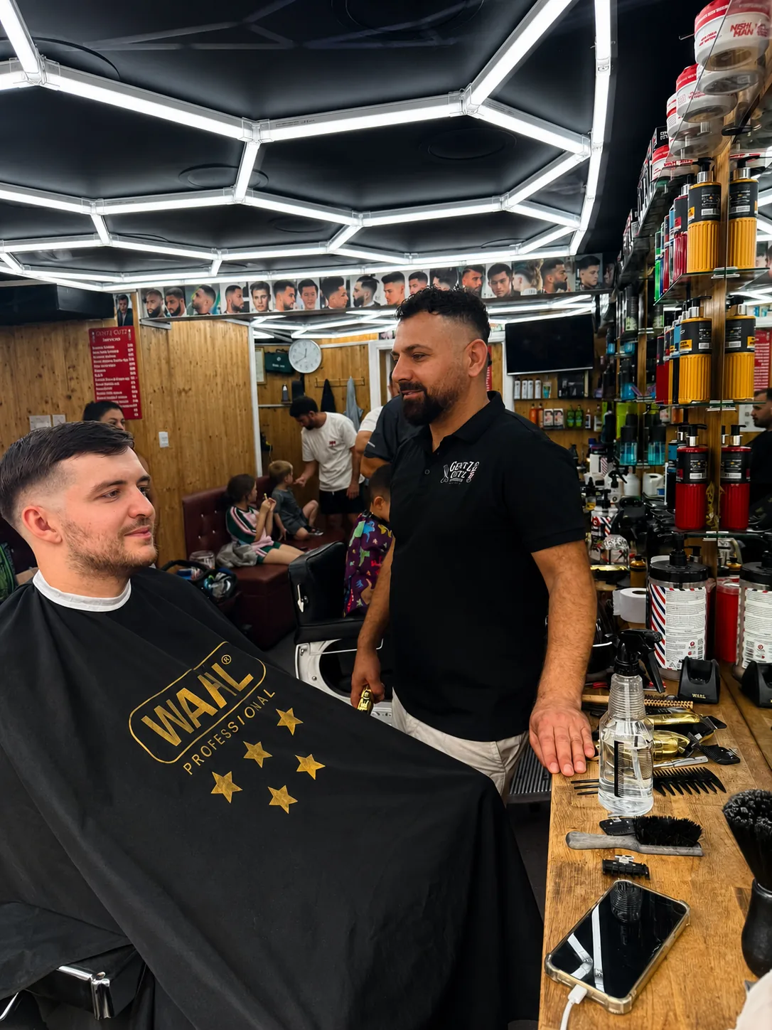 Owner of Gentz Cutz beside a client in the barber chair